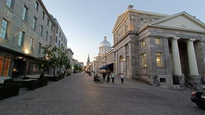 A cobblestone street in Old Montréal lined with heritage stone buildings at dusk.