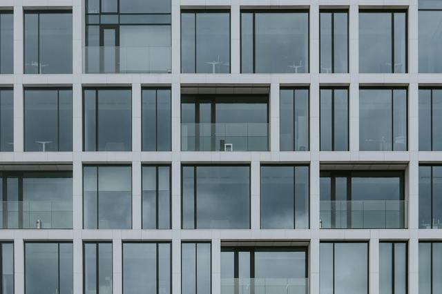 A modern building facade forming a regular grid of identical glass windows.