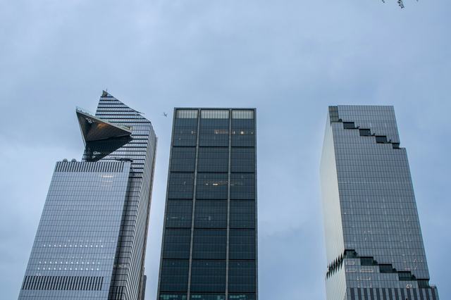 Three office towers seen from street level against an overcast sky.